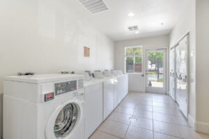 Interior Laundry Facilities, 6 washing machines, 6 dryers, tile floor, pool entrance adjacent to laundry facilities.